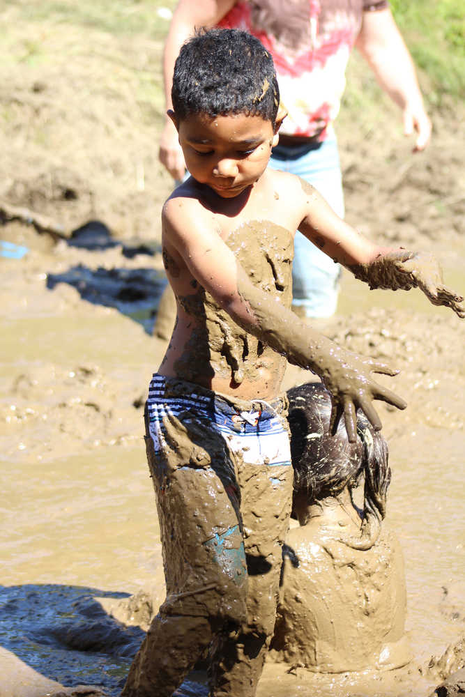 Zaine Beckworth looks down at the mud covering him as he wades through the mud pit at the 2016 Mud Wallow at Cottonwood Park on July 17.