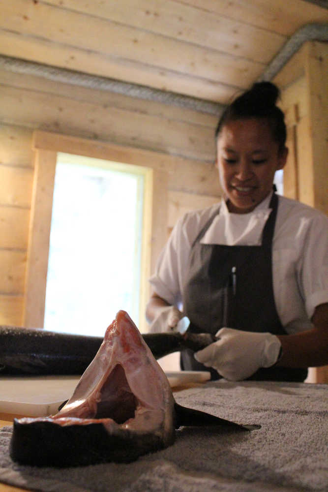 Aisha Ibrahim, Tutka Bay Lodge's chef for the 2016 summer season, demonstrates how to filet a salmon in The Tutka Bay Cooking School. Tutka Bay offers cooking classes held on the Widgin II. a repurposed crabbing boat on the lodge's property.-Photo by Anna Frost, Homer News