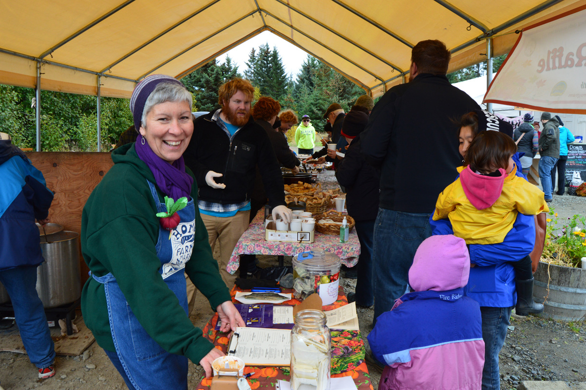 Margarida Kondak sells tickets for a turkey raffle at last Saturday’s end-of-season party at the Homer Farmers Market. Behind her, volunteers serve free soup, bread and desserts to shoppers.-photo by Annie Rosenthal