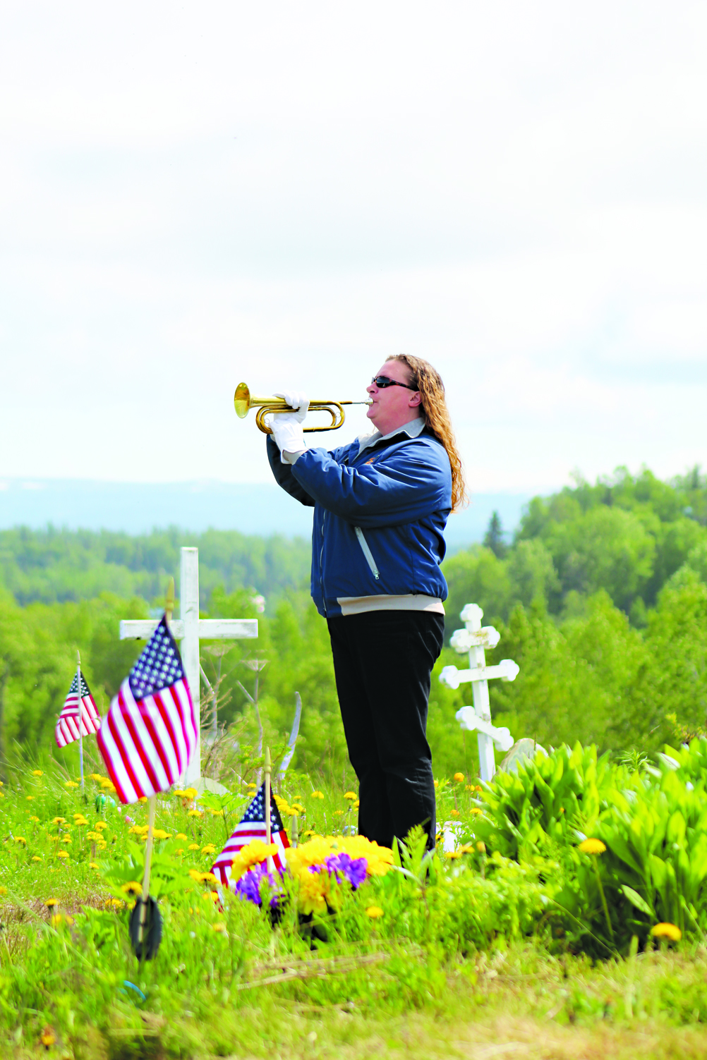 Homer resident Christie Hill, who has been a bugle player for the Memorial Day services for about 10 years, plays “Taps” at the Ninilchik Cemetery on Monday, May 30. -Photo by Anna Frost, Homer News