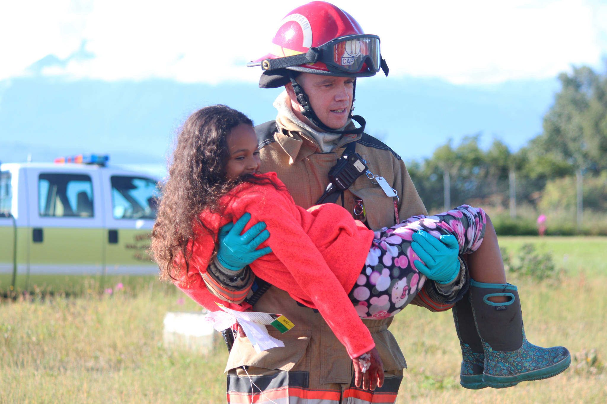 Captain Tim Yarbrough, of the Homer Volunteer Fire Department, carries Jaelynn Cabana away from a simulated plane crash Saturday, Aug. 19, 2017 at the Homer Airport in Homer, Alaska. The simulated crash was part of an emergency drill that tests the ability of airport personnel and local emergency responders to handle a number of scenarios at the airport. (Photo by Megan Pacer/Homer News)