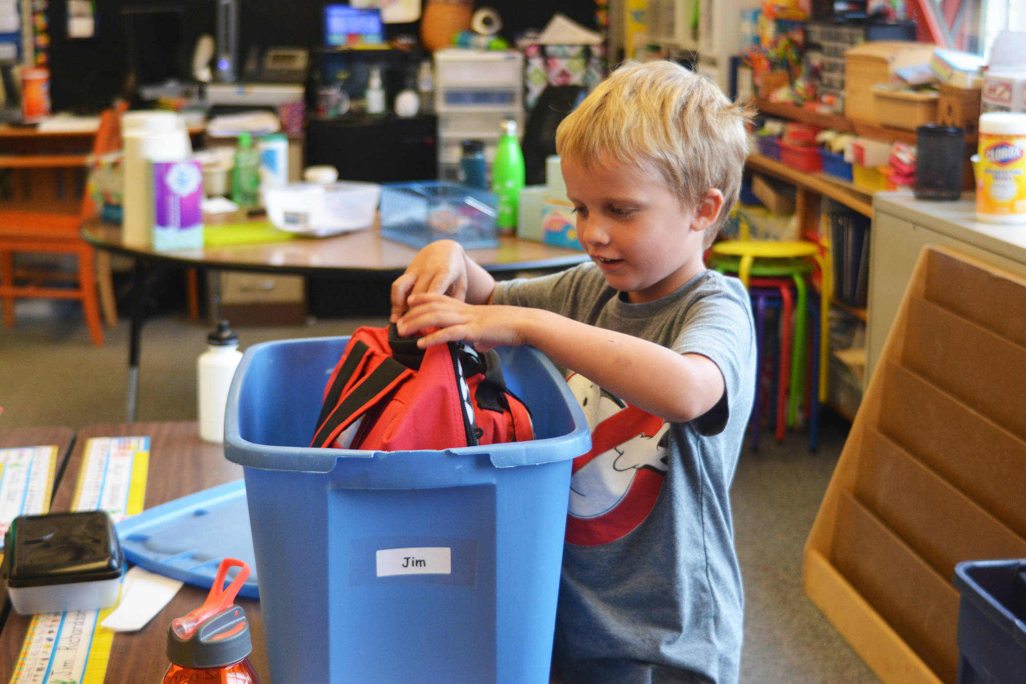 Jim Richardson, a student in Mrs. Marion’s kindergarten class at Paul Banks Elementary, digs out his outdoor clothes and shoes from a bin in preparation for recess on the first day of school Tuesday, Aug. 22, 2017 at the school in Homer, Alaska. (Photo by Megan Pacer/Homer News)