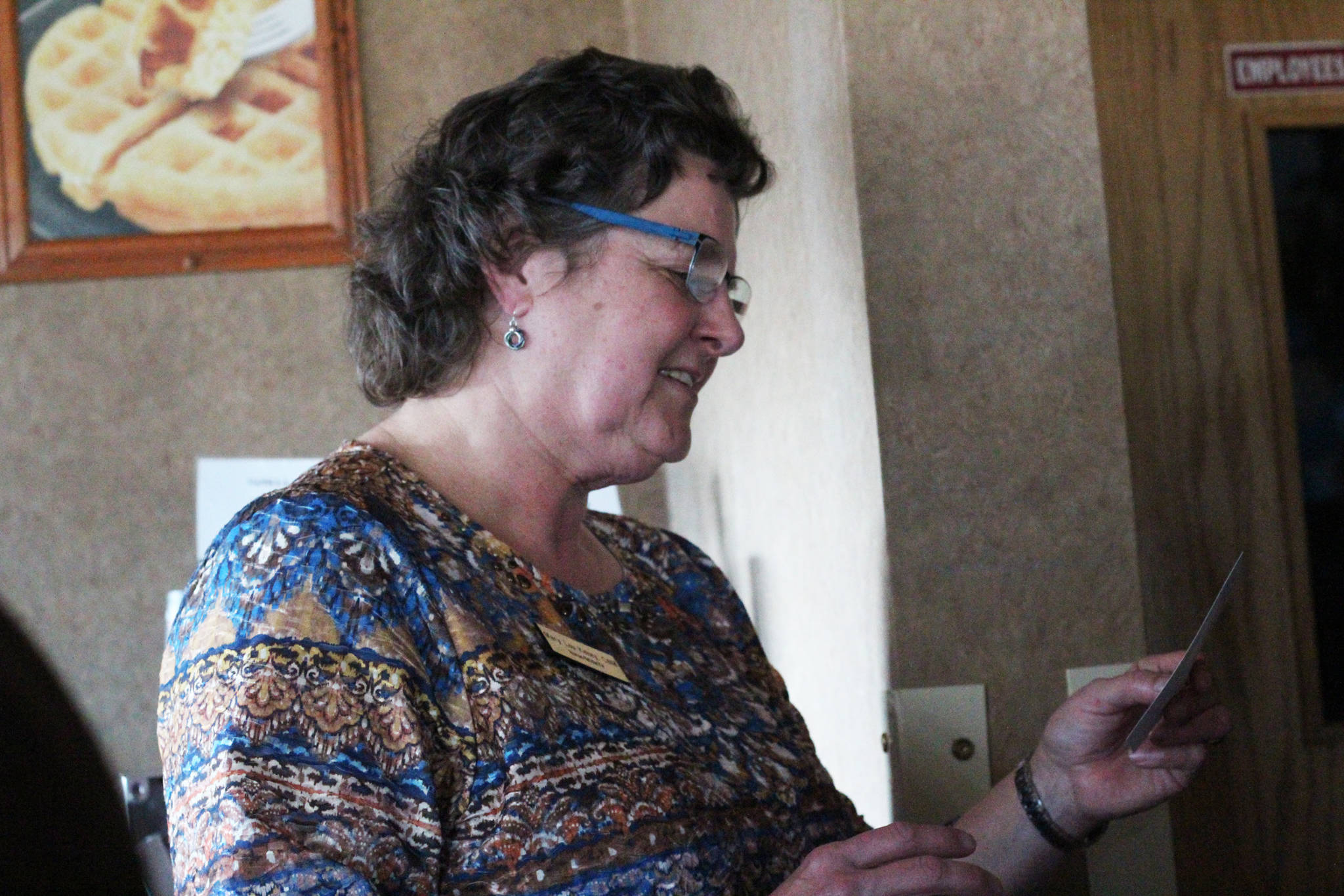 Mary Lou Kelsey, a certified nurse midwife who has practived in Homer for around 35 years, looks at a photo during a retirement party held for her Friday, Oct. 13, 2017 at the Best Western in Homer, Alaska. (Photo by Megan Pacer/Homer News)