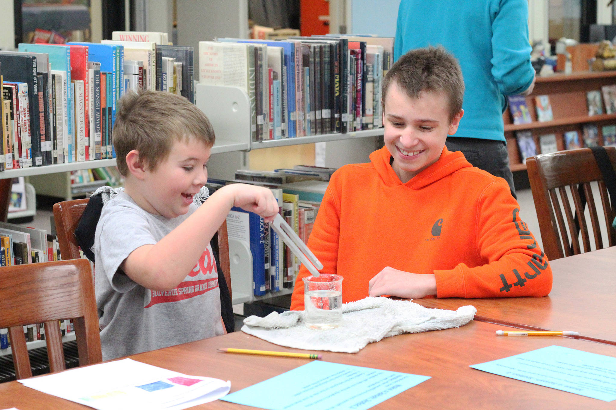 Colt Krueger (left) reacts to a sound experiment while working with Homer Middle School eighth grader Gabe Dash during a mentor lesson Tuesday, Oct. 24, 2017 at Homer Middle School in Homer, Alaska. Krueger and his fellow Paul Banks Elementary first grade classmates each paired up with a middle school student and completed five different stations in a new mentorship program between the schools. (Photo by Megan Pacer/Homer News)