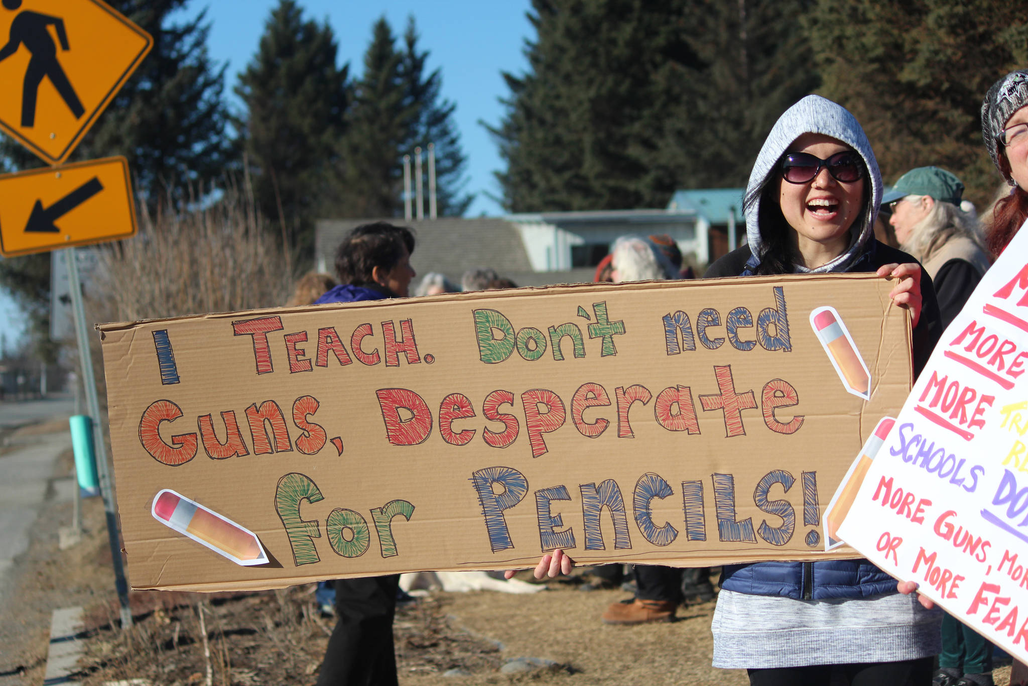 Homer Flex teacher Lindsay Martin holds a cardboard sign reading “I teach. Don’t need guns, desperate for pencils!” at a rally to support the national March for Our Lives on Saturday, March 24, 2018 at WKFL Park in Homer, Alaska. Martin said she doesn’t think those who suggest arming teachers do so out of malice, but that she does not see it as a viable solution to gun violence in schools. Dozens of Homer residents gathered with similar messages at the park Saturday in an impromptu rally organized by the Homer chapter of Citizens Action Network. (Photo by Megan Pacer/Homer News)