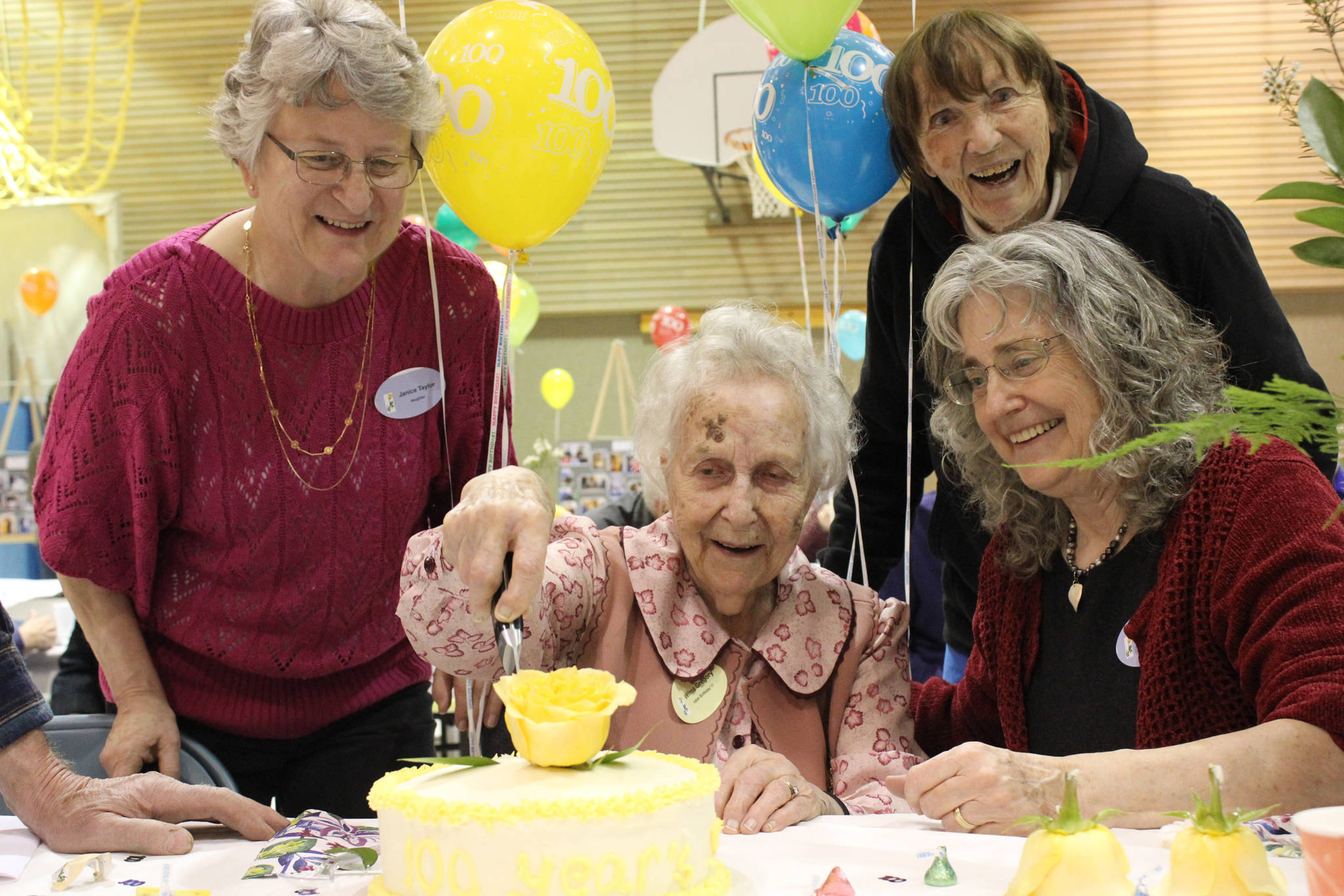 Wilma Gregory, center, cuts into a cake in celebration of her 100th birthday on Saturday. Helping are Gregory’s daughters Janice Taylor of Juneau, left, and Gayle Forrest of Homer, right. Friend Randi Somers of Homer, back, looks on. (Photo by McKibben Jackinsky)