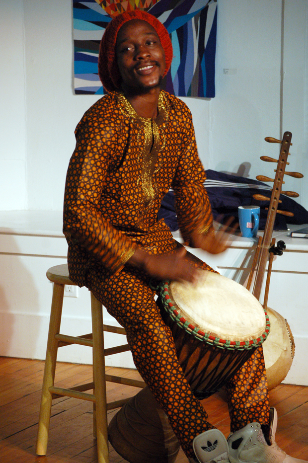 Soriba Fofana plays the djembe drum at an artists’ talk on Sunday at Bunnell Street Arts Center. His n’goni is in the background.-Photo by Michael Armstrong, Homer News