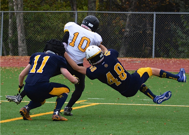 Homer cornerback Hunter Edens (No. 11) and wide receiver Zach McKenna (No. 48) tackle a Voznesenka player during Saturday’s homecoming game.-Photo by Betsy Wolf