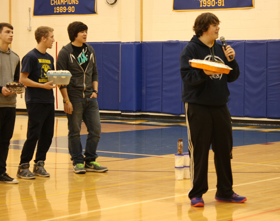 While teammates wait to auction their offerings at Meet the Mariners, a basketball team fundraiser held at the Homer High gym last Saturday, Mariner Paul Trowbridge, right, tempts the crowd with a homemade carrot cake.-Photo by Lindsay Olsen for the Homer News