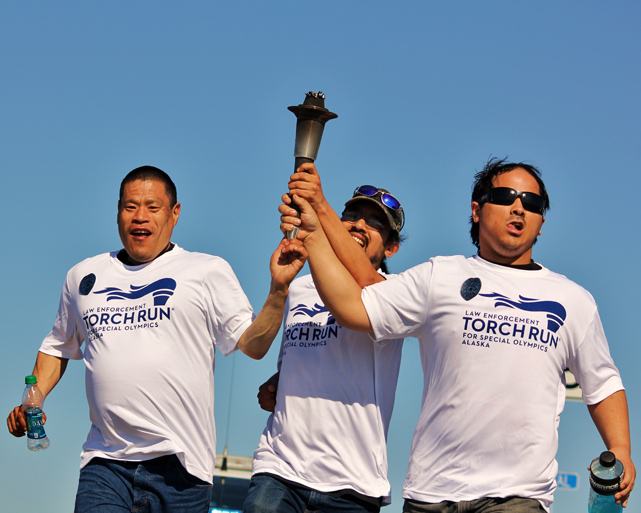 Ivan Meganack, Nick Kvasnikoff and Brent Guarin Escolta cross the finish line of the Homer Torch Run on Saturday. “When I saw them coming across the finish holding the torch together, I saw everything the special olympics stands for,” said photographer Russell Campbell.