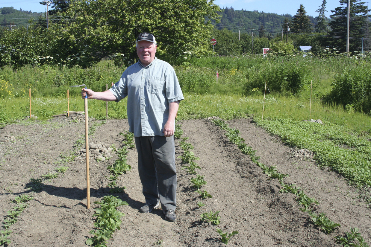 Father Robert Leising tends the garden at St. John the Baptist Catholic Church.-Photo by Toni Ross