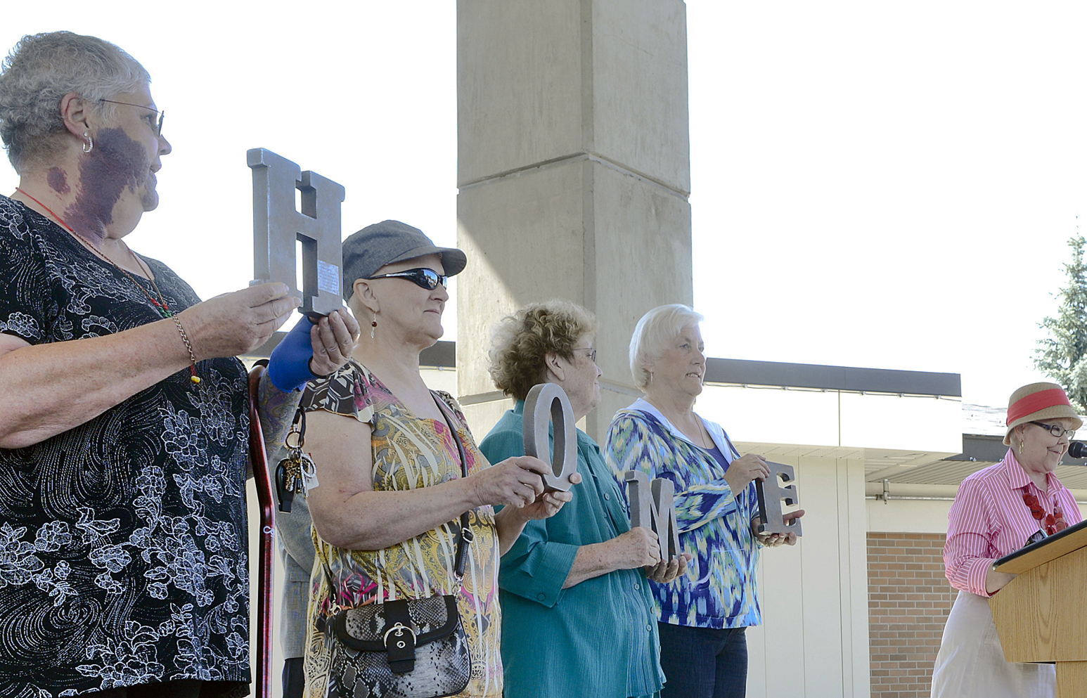 From left, Pamela Hansen, Barbara Caswell, Nancy Egbert and Sue Carter hold up the word “home”as Kenai Mayor Pat Porter speaks during the opening ceremony of Central Peninsula Hospital’s Radiation Oncology Center on July 10 in Soldotna.-Photo by Rashah McChesney, Morris News Service - Alaska