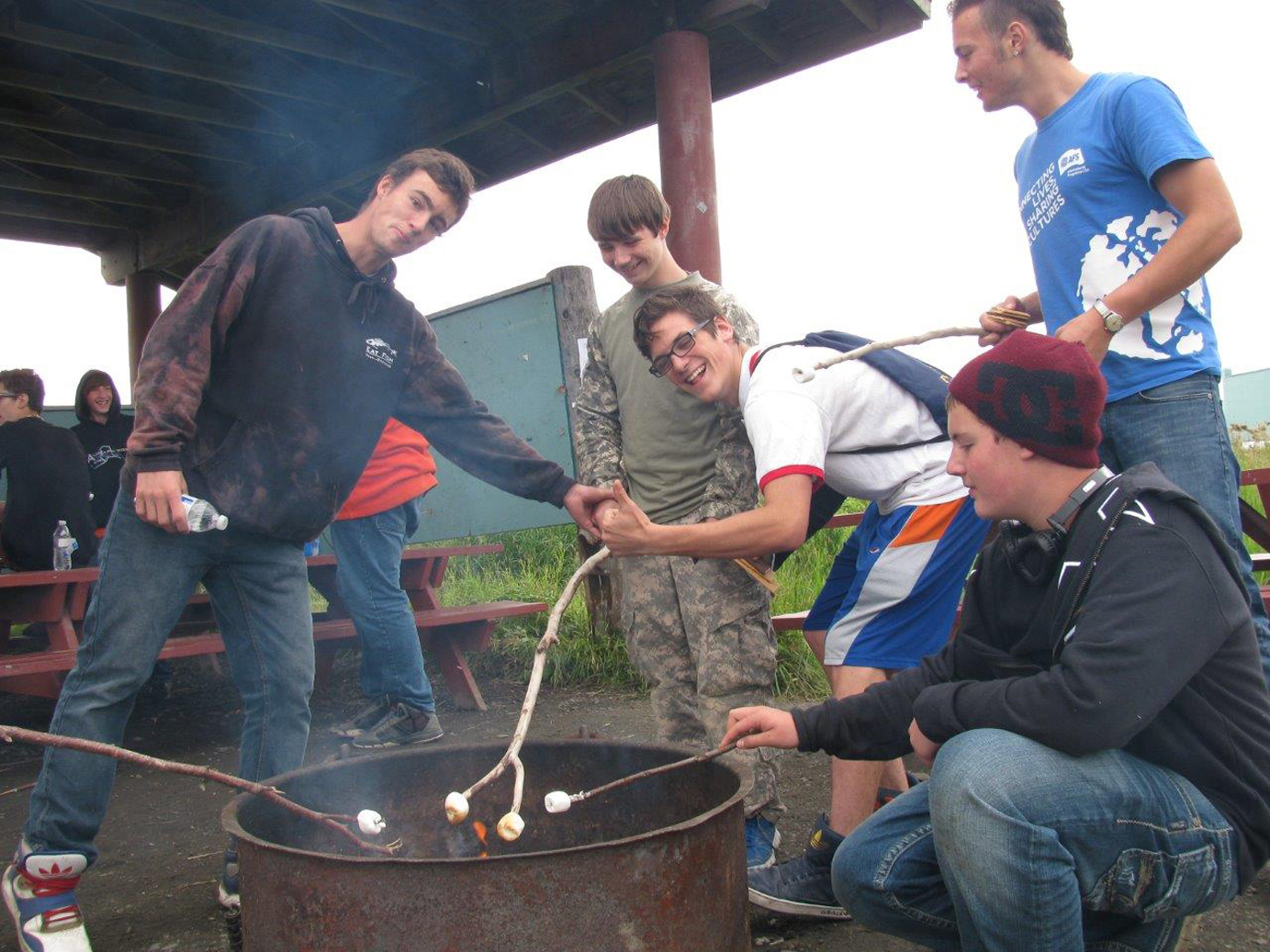 From left, senior Quinn Daugharty, freshman Bradley Bordner, seniors Gabe Selbig and Mario Wettach-Glosser, and freshman Kyler Mahoney (kneeling) roast marshmallows at a peer-mentoring get-together for Homer High School seniors and freshmen.-Photo provided