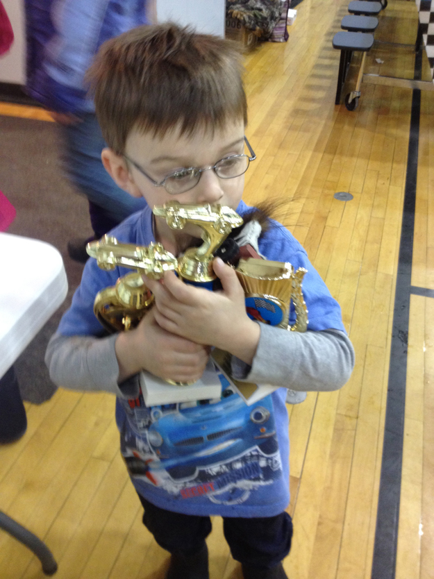 Four-year-old Jackson Woodhead claims trophies he received during the Snow Rondi’s pinewood derby. He also went home with an armload of trophies, ribbons and candy bars he won in ski events.-Photo provided