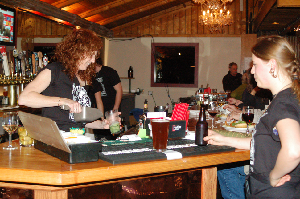 Kat Clarke, left, mixes a drink while Sunrose Olson, right, waits at the reopening last Friday of Alice’s Champagne Palace. -Photo by Michael Armstrong, Homer News