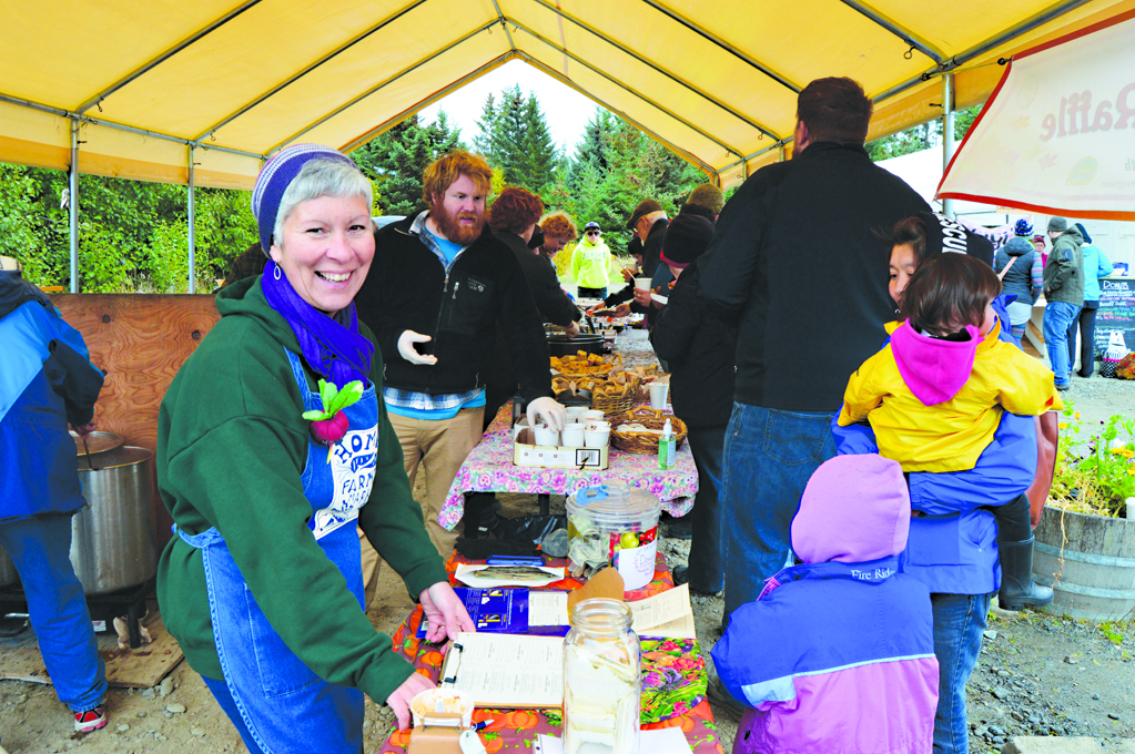 Margarida Kondak sells tickets for a turkey raffle at the 2015 end-of-season party at the Homer Farmers Market. Behind her, volunteers serve free soup, bread, and desserts to shoppers.-Homer News file photo