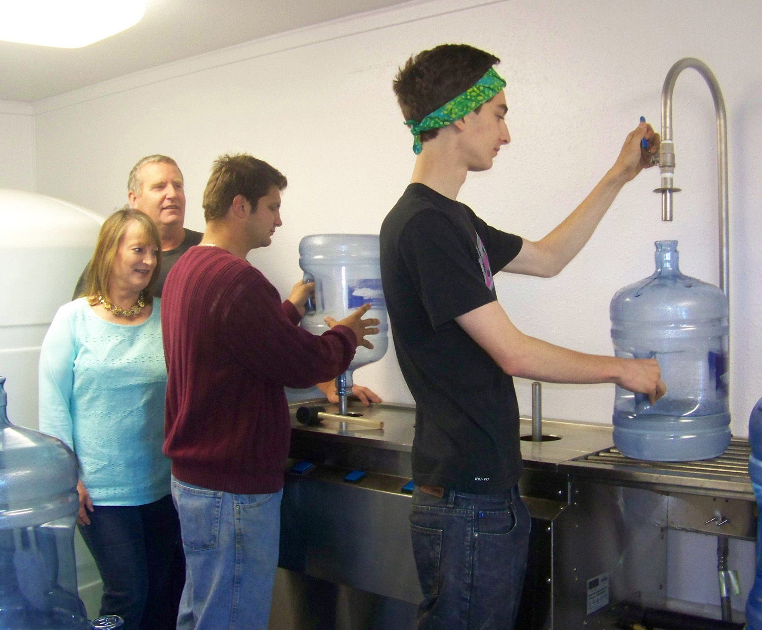 Ohlson Mountain Mineral Springs H2O owners Mary Lou and William Strutz look on while employees Alex Stuart and Jake Worsfold clean and fill bottles. -Photo by McKibben Jackinsky, Homer News