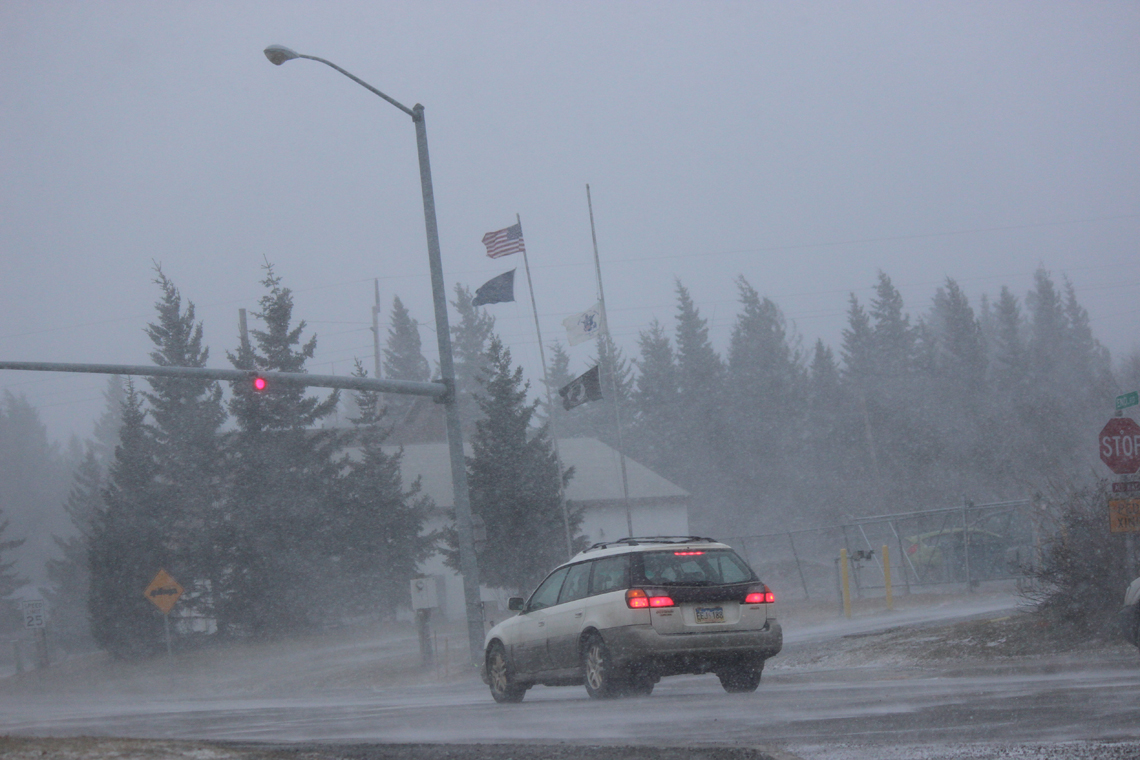 Flags snap and snow swirls as winds increase around noon on Friday.