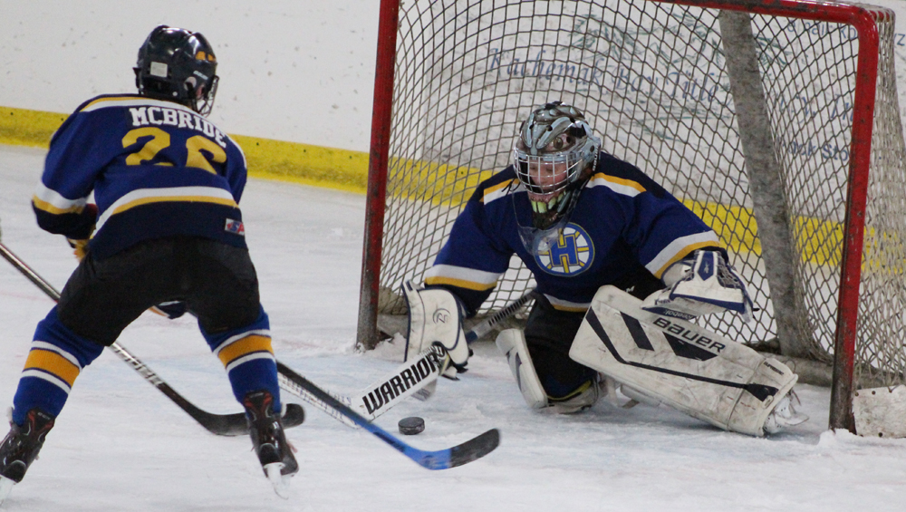 Homer goalie Keegan Strong passes the puck from a failed Kenai goal attempt for Dylan McBride to sweep away from the net.-Photo by Anna Frost, Homer News