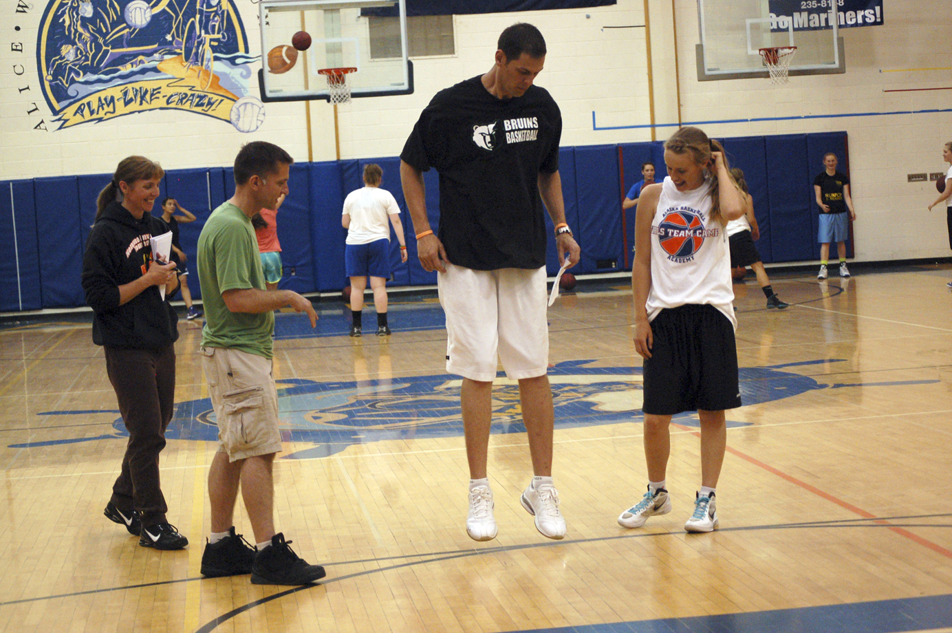 Matt Garrison, center, gives Kayla Stafford, right, a Nikolaevsk School basketball player, some pointers at the Bruins Basketball Shooting Clinic last Friday at Homer High School as Bea Klaich, left, and Chris Etzwiler, second from left, watch.-Photo by Michael Armstrong, Homer News