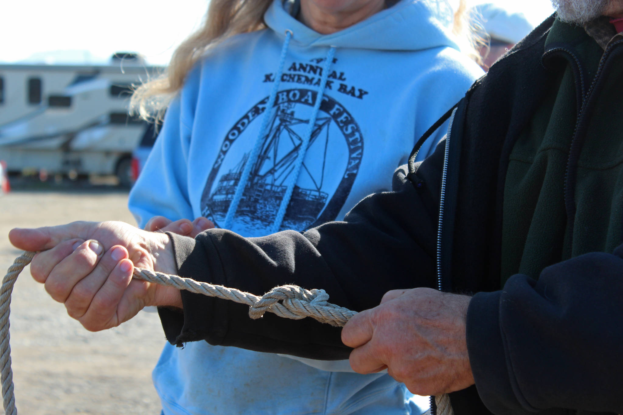 Richard “Bumppo” Bremicker, president of the Kachemak Bay Wooden Boat Society, shows Carol Sacheck how to tie a bowline knot Saturday, Sept. 1, 2018 during the Kachemak Bay Wooden Boat Festival on the Homer Spit in Homer, Alaska. (Photo by Megan Pacer/Homer News)