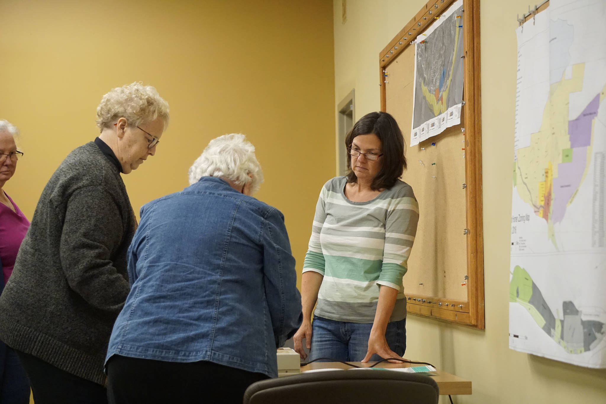 Homer City Clerk Melissa Jacobsen, right, watches as Election Canvass Board members Maryann Lyda, left, and Alice Krivitsky, center, feed ballots through an AccuVote machine during the Oct. 5, 2018, meeting of the canvass board in Homer, Alaska. The board counted the absentee and other ballots uncounted on Tuesday’s election. The overall result did not change, with Ken Caster winning the election of Homer Mayor and Donna Aderhold and Heath Smith winning re-election to the Homer City Council. (Photo by Michael Armstrong/Homer News)