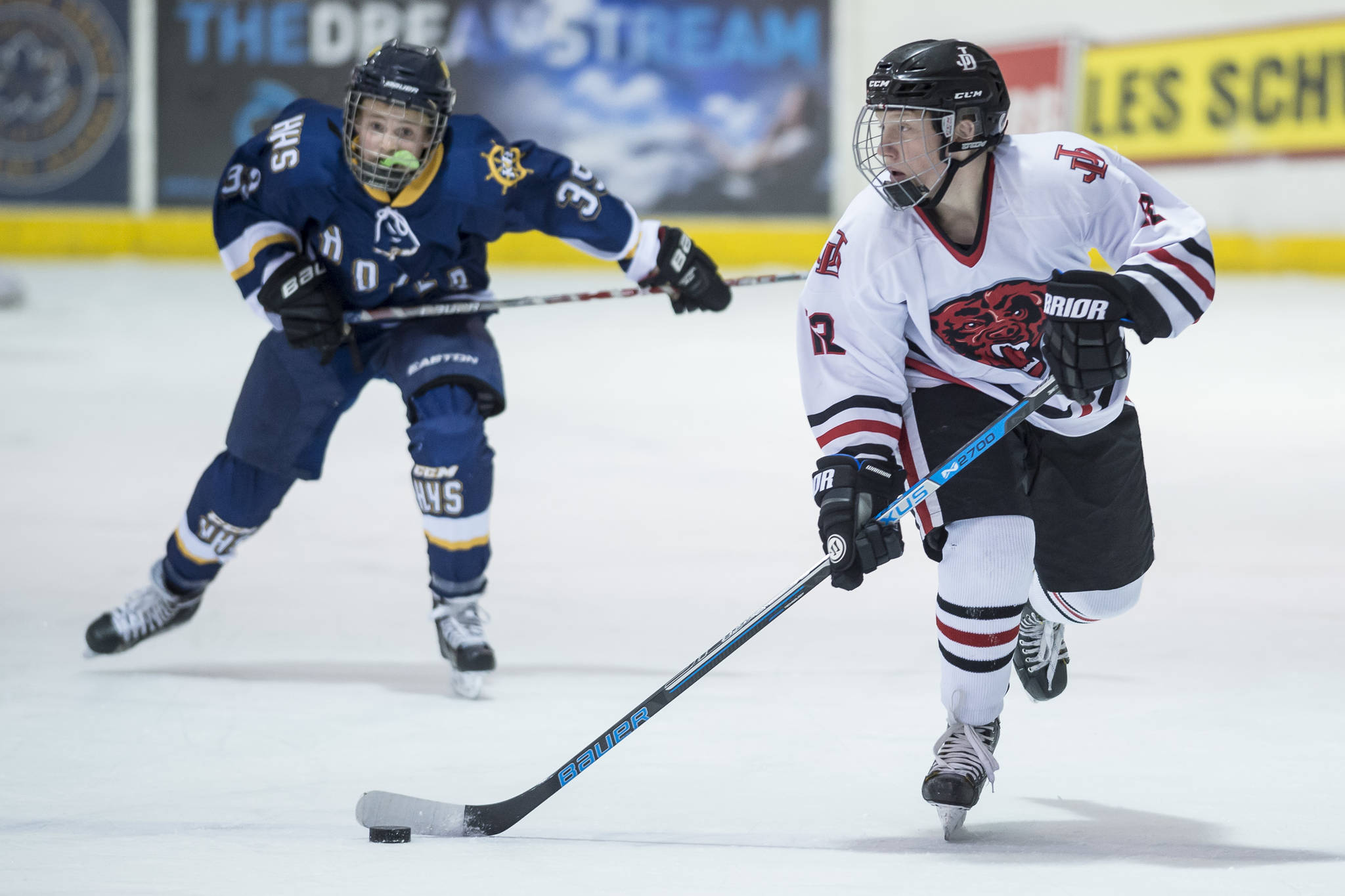 Juneau-Douglas’ Kyler Alderfer, right, moves the puck in front of Homer’s Casey Otis at Treadwell Arena on Friday, Jan. 18, 2019. JDHS won 4-3 in overtime. (Michael Penn/Juneau Empire)