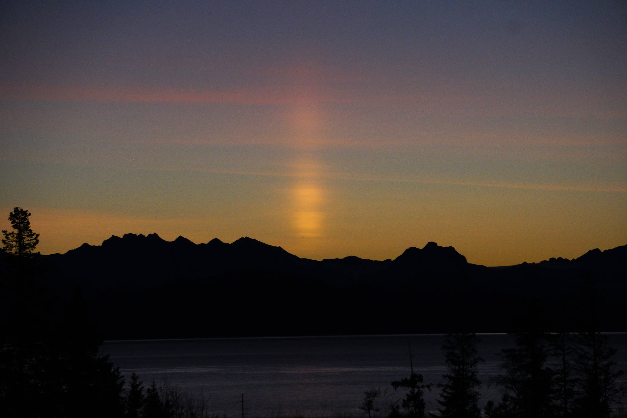 A sun pillar appears over the Kenai Mountains at sunrise about 9:20 a.m. Friday, Jan. 18, 2019, in Homer, Alaska. A sun pillar forms when light from the rising or setting sun is reflected by ice crystals in thin, high-level clouds. (Photo by Michael Armstrong/Homer News)