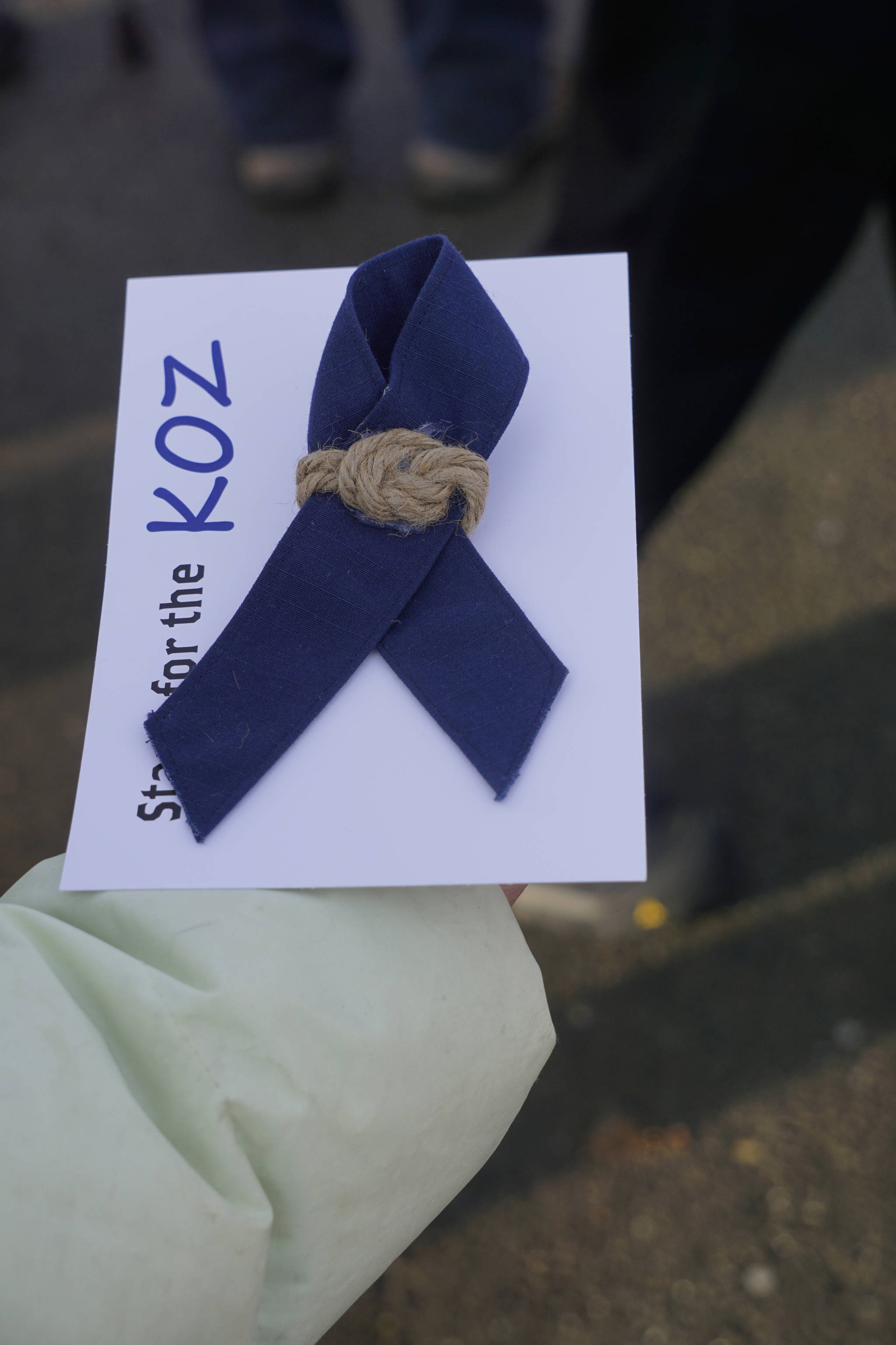 Nona Safra holds a ribbon handed out for Chief Warrant Officer Michael Kozloski on Friday morning, Feb. 8, 2019, at the Seafarer’s Memorial on the Homer Spit, Homer, Alaska. The blue fabric is from Coast Guard utility uniforms. (Photo by Michael Armstrong/Homer News)