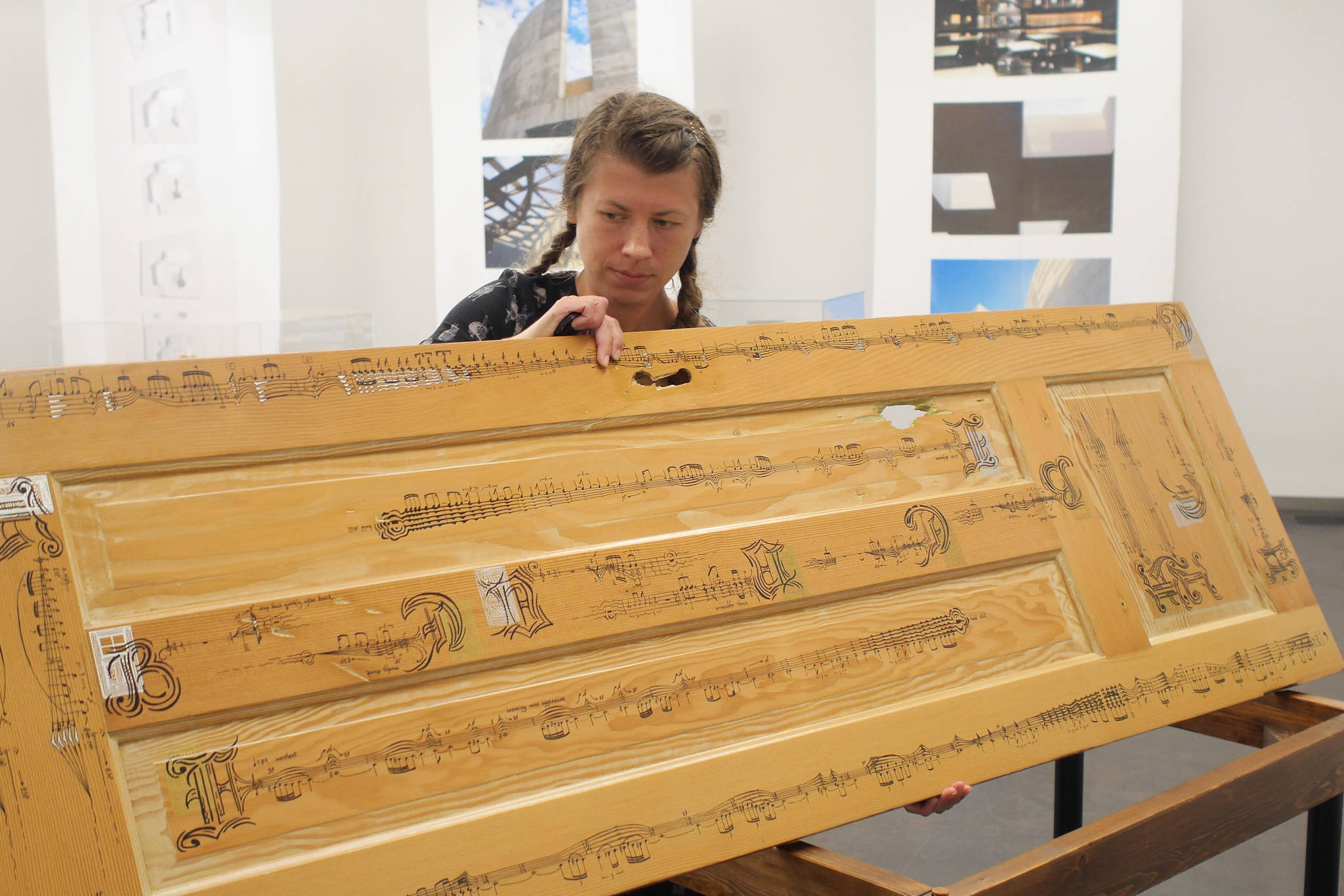 In this undated photo, Anna Pigdorna stands by her piece, “Through Closed Doors.” The arrangement of music on the door is designed so that musicians performing the piece must physically move around the door to act out dramatic dimensions of the piece. (Photo provided)