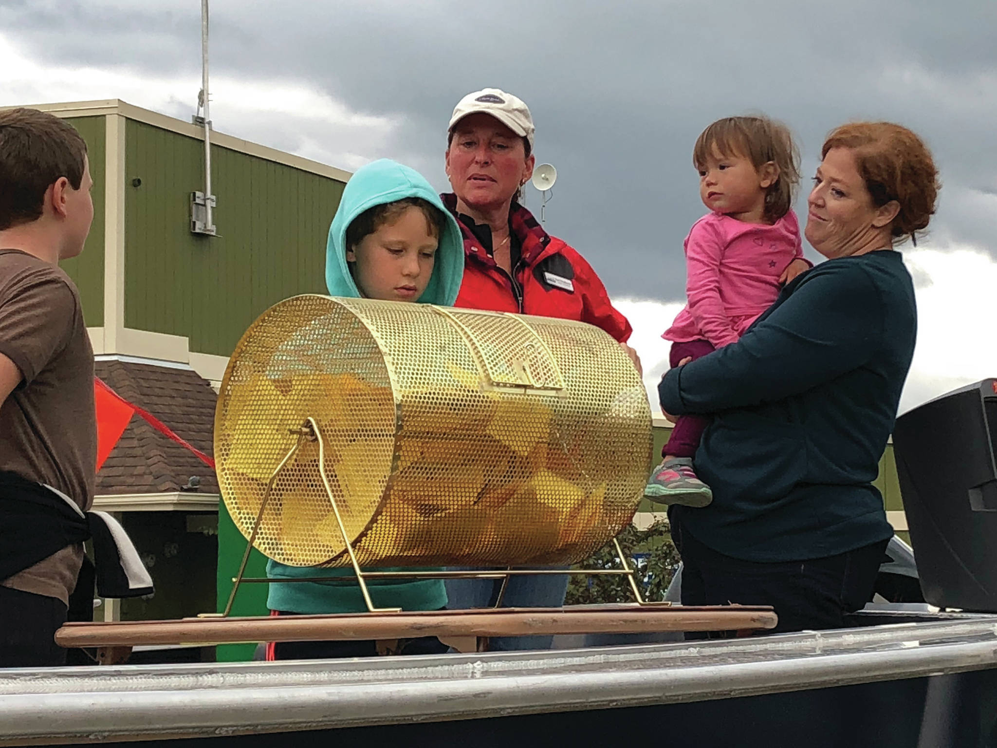 Jack and Ben Engebretsen, sons of Bay Weld general manager Erik Engebretsen, draw the winning ticket for the Homer Chamber of Commerce and Visitor Center Bay Well skiff contest as chamber board secretary Kari Dendurent, center, and chamber executive director Debbie Speakman, with daughter Alice, watch. The drawing was held on Sept. 2, 2019, at Grace Ridge Brewery in Homer, Alaska. (Photo provided)