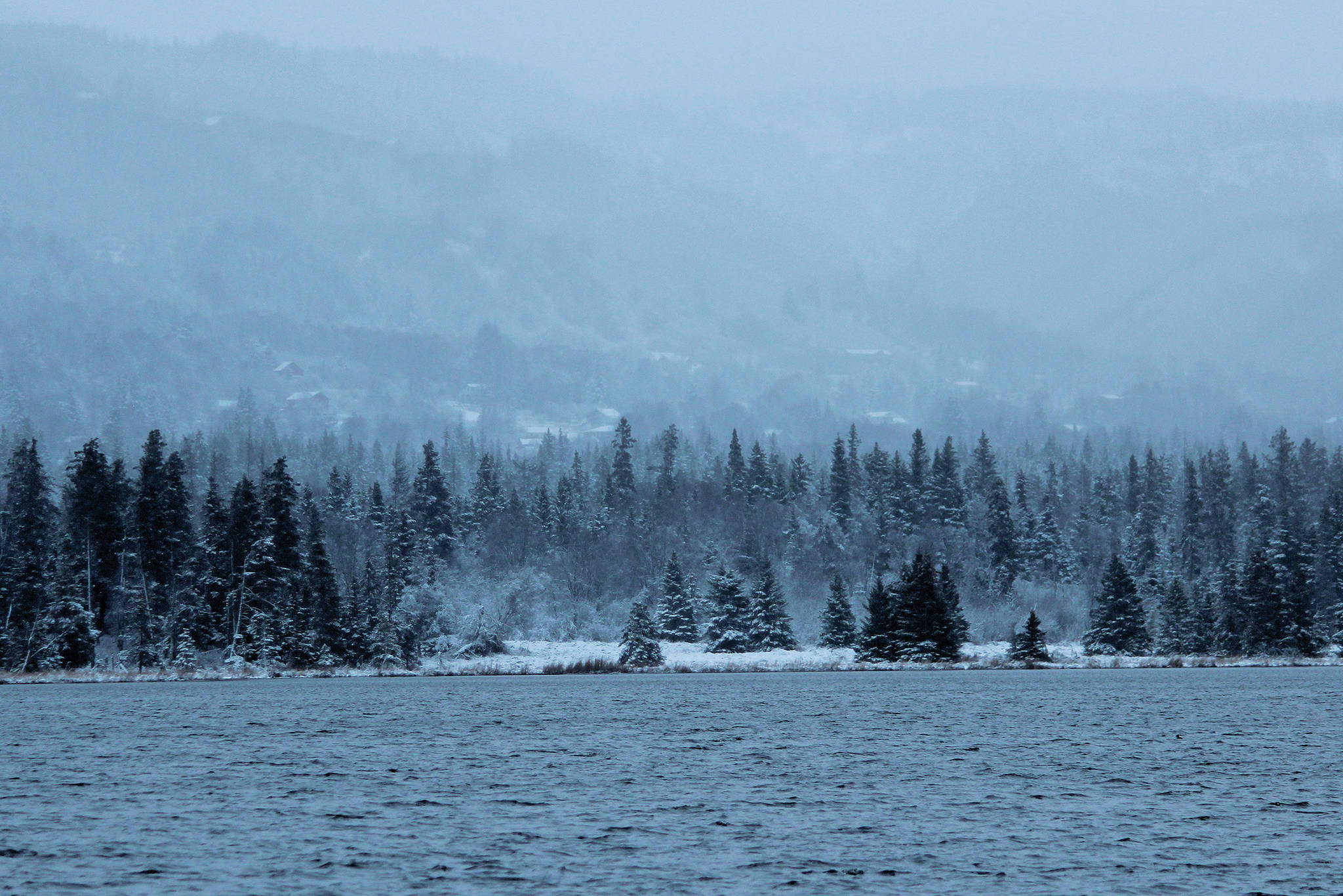 Snow and fog creep up the ridges above Homer on Monday, Dec. 2, 2019 as seen from across Beluga Lake in Homer, Alaska. Homer got its first dump of snow that stuck around on Sunday evening. (Photo by Megan Pacer/Homer News)