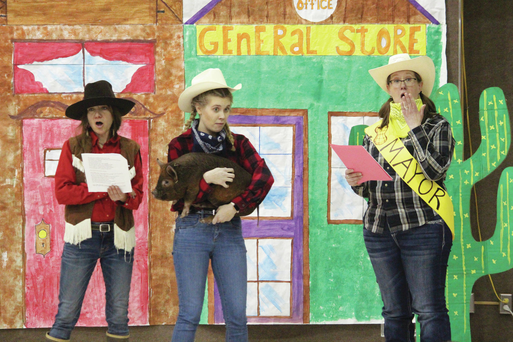 Paul Banks staff members Brandi Scott (left) Elissa Newell (center) and Julie Gottfried (right) perform a skit for students on Feb. 3, 2020 at the elementary school in Homer, Alaska. The school puts on a celebratory assembly each year for the start of the annual read-a-thon. (Photo by Megan Pacer/Homer News)