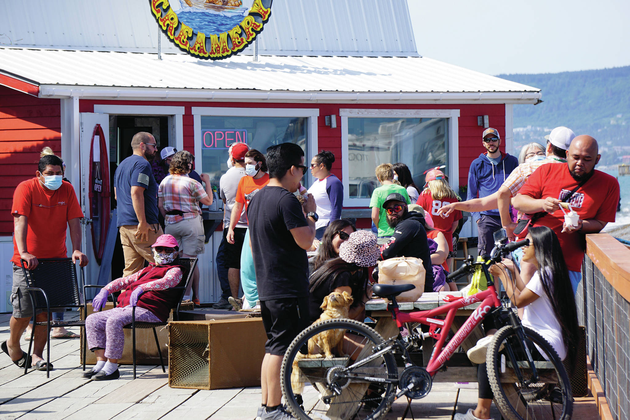 Visitors enjoy the sun on July 4, 2020, on a deck at a Homer Spit boardwalk in Homer, Alaska. In a press conference on Tuesday, July 7, 2020, Alaska Chief Medical Officer Dr. Anne Zink advised people to minimize the risk of getting infected by COVID-19 by avoiding crowded spaces. (Photo by Michael Armstrong/Homer News)