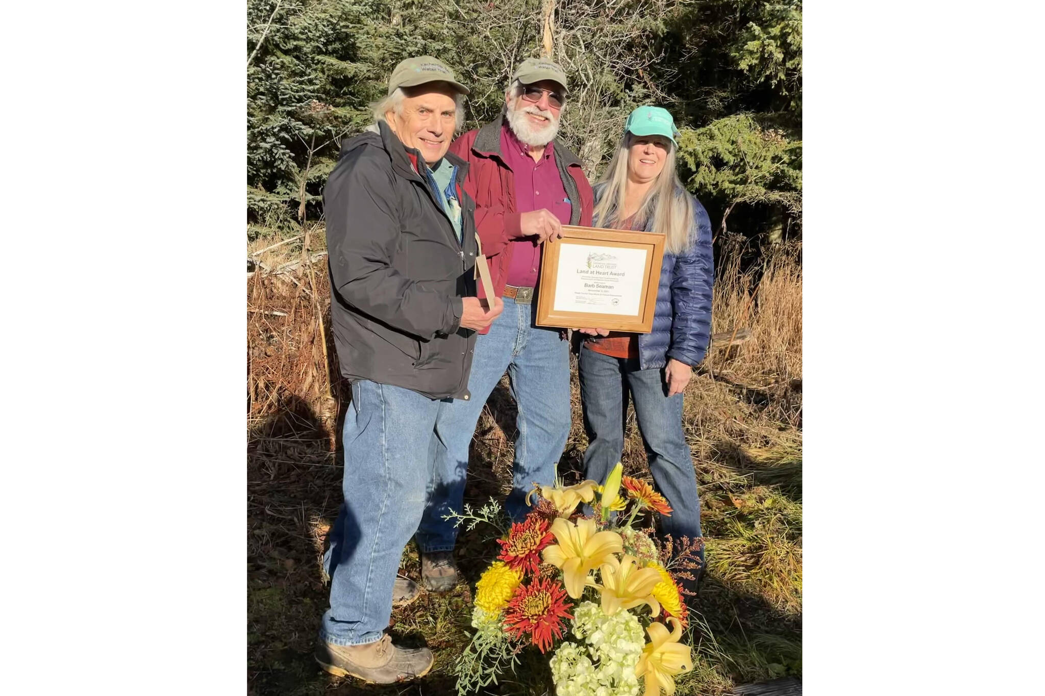 Dave Brann and Robert Archibald present Barb Seaman with the Kachemak Heritage Land Trust Land at Heart Award on Nov. 9 at the Calvin & Coyle Trail in Homer. (Photo provided by Kachemak Heritage Land Trust)