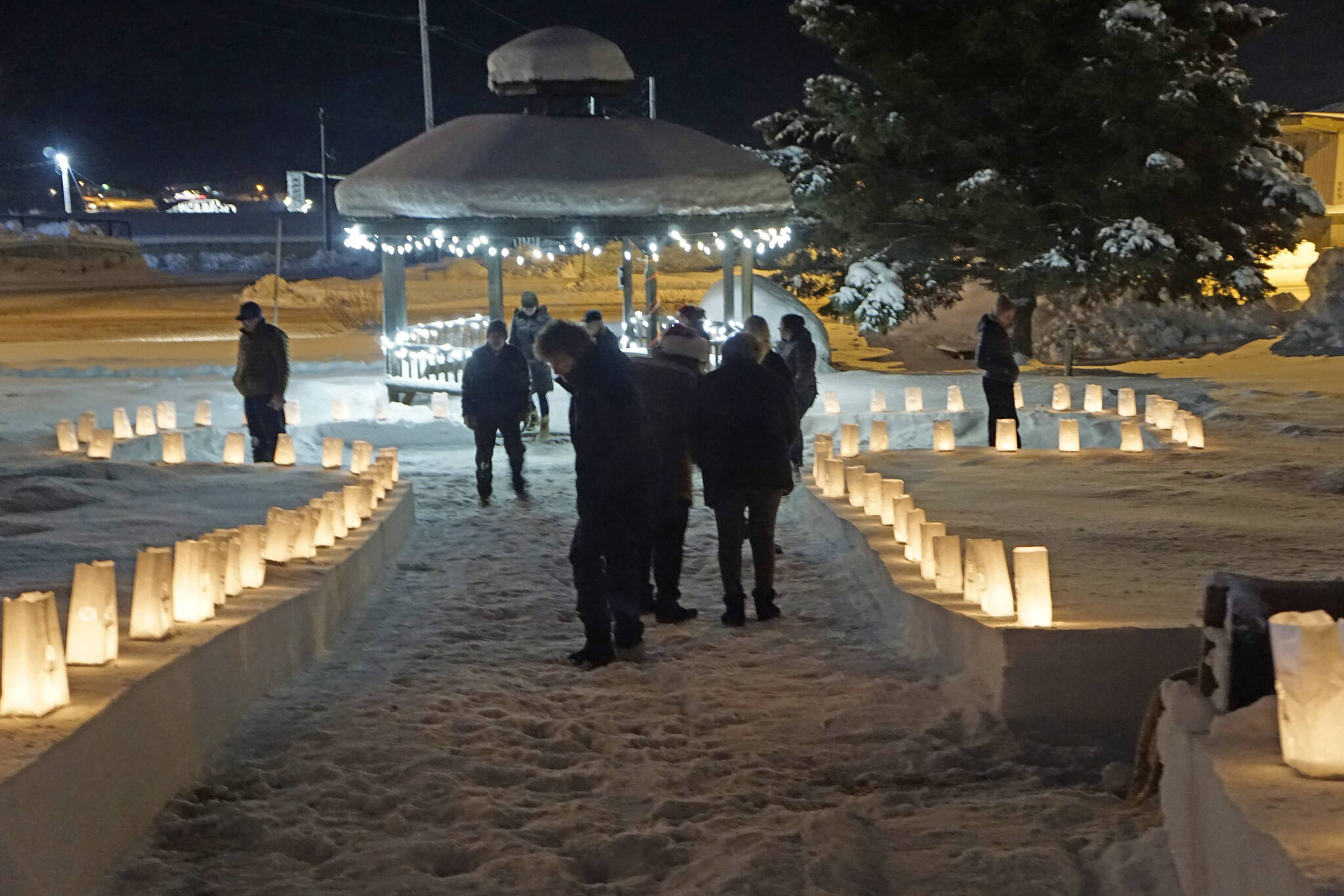 People look at memorial luminarias on Thursday, Dec. 16, 2021, for Hospice of Homer's "LIght Up a Life" event at WKFL Park in Homer, Alaska. (Photo by Michael Armstrong/Homer News)