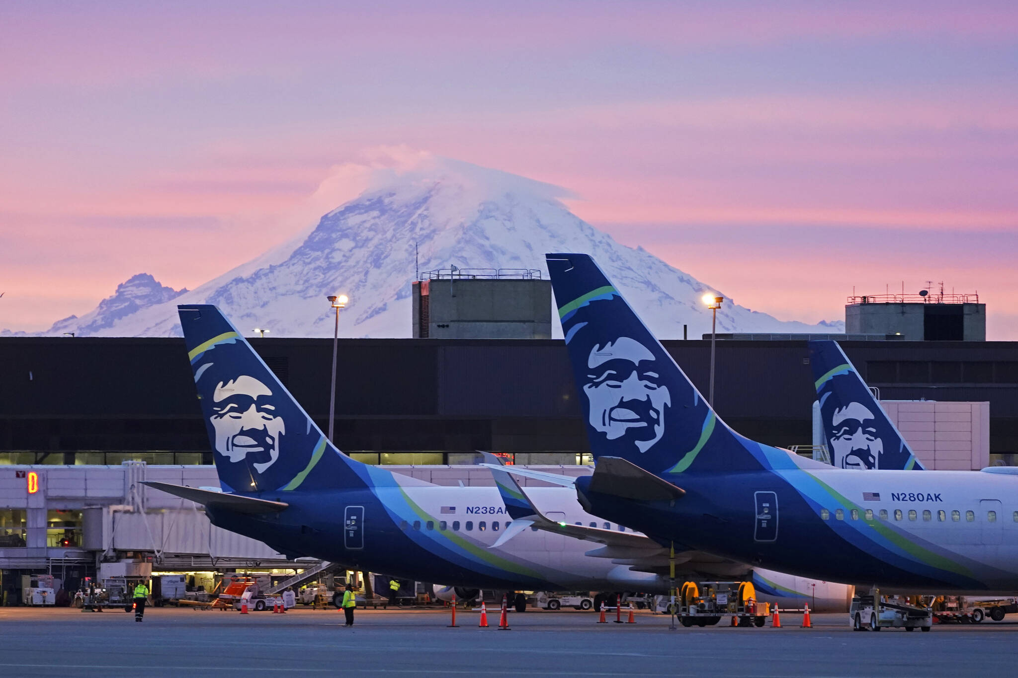 AP Photo / Ted S. Warren, File
Alaska Airlines planes are parked at gates with Mount Rainier in the background at sunrise, March 1, 2021, at Seattle-Tacoma International Airport in Seattle. Alaska Airlines said Thursday, Jan. 6, 2022, it will trim its schedule by about 10% for the rest of January at it deals with “unprecedented” numbers of employees calling in sick during the current COVID-19 surge.