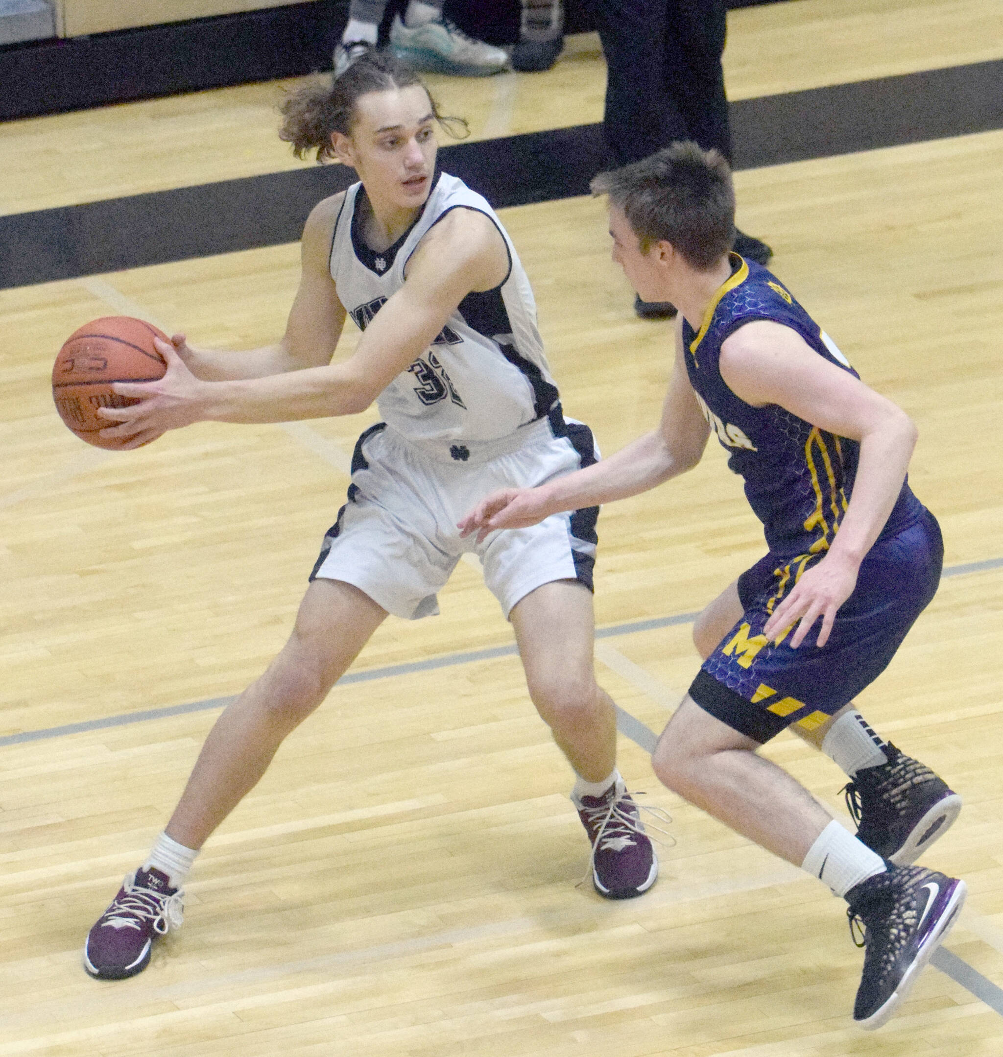 Nikiski’s Seth Payne looks to pass under pressure from Homer’s Peyton Edens on Tuesday, Jan. 25, 2022, at Nikiski High School in Nikiski. (Photo by Jeff Helminiak/Peninsula Clarion)