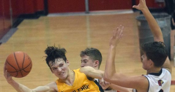 Ninilchik's Justin Trail saves the ball in front of Kenai Central's Luke Armstrong and Eli McCubbins on Saturday, March 5, 2022, at Kenai Central High School in Kenai, Alaska. (Photo by Jeff Helminiak/Peninsula Clarion)