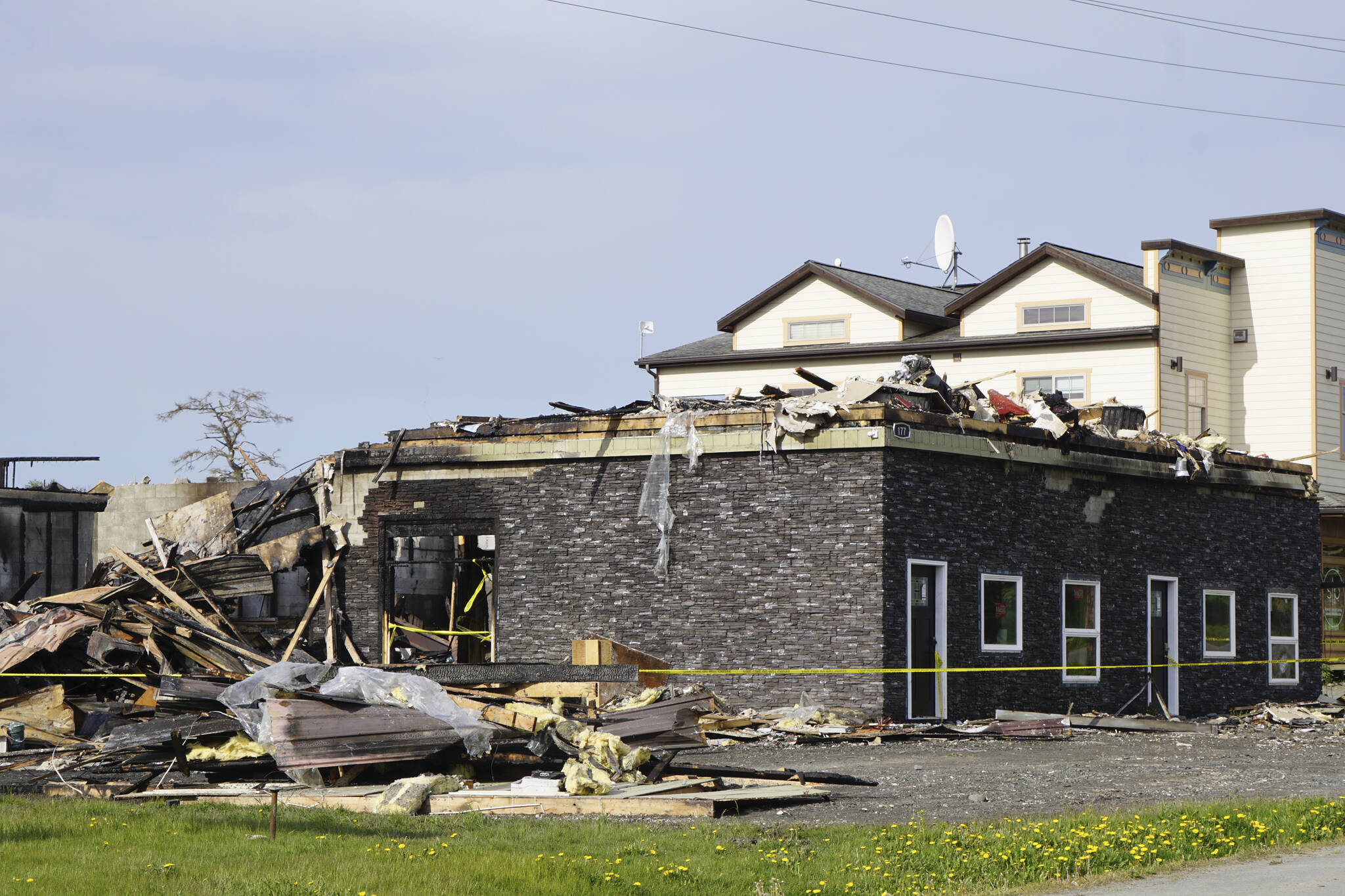 The bottom story is all that is left of a building at 177 E. Bunnell Ave. that caught fire early Saturday morning, June 4, 2022, in Homer, Alaska. Two people and their pets living in an apartment on the side closest to the road escaped injury. Homer Volunteer Fire Department, Kachemak Emergency Services and Western Emergency Services worked until about noon on Saturday to fully extinguish the fire. The Compass Rose Building to the right had some minor damage such as cracked windows from heat exposure. (Photo by Michael Armstrong/Homer News)