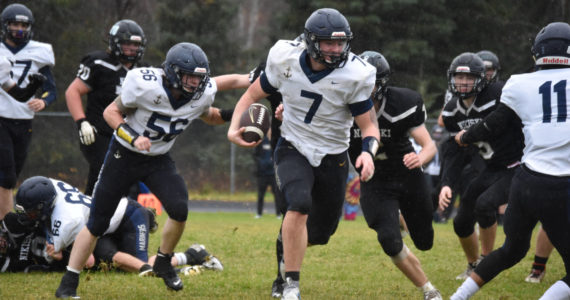 Homer's Carter Tennison runs with the ball, pursued by several Bulldogs, during the playoff game on Saturday, Oct. 8, 2022, at Nikiski Middle/High School in Nikiski, Alaska. (Jake Dye/Peninsula Clarion)