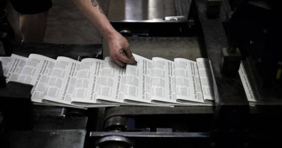 Mike Tullar grabs a Herald to check over as the first papers roll off the press on Wednesday, March 30, 2022 in Everett, Washington. (Olivia Vanni / The Herald)