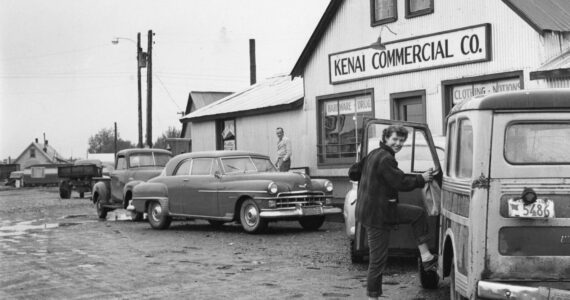 [1a—] After doing business in the Kenai Commercial Company store, Rusty Lancashire climbs into family station wagon, with its sagging back bumper, to head for home. (1954 photo by Bob and Ira Spring for Better Homes & Garden magazine)