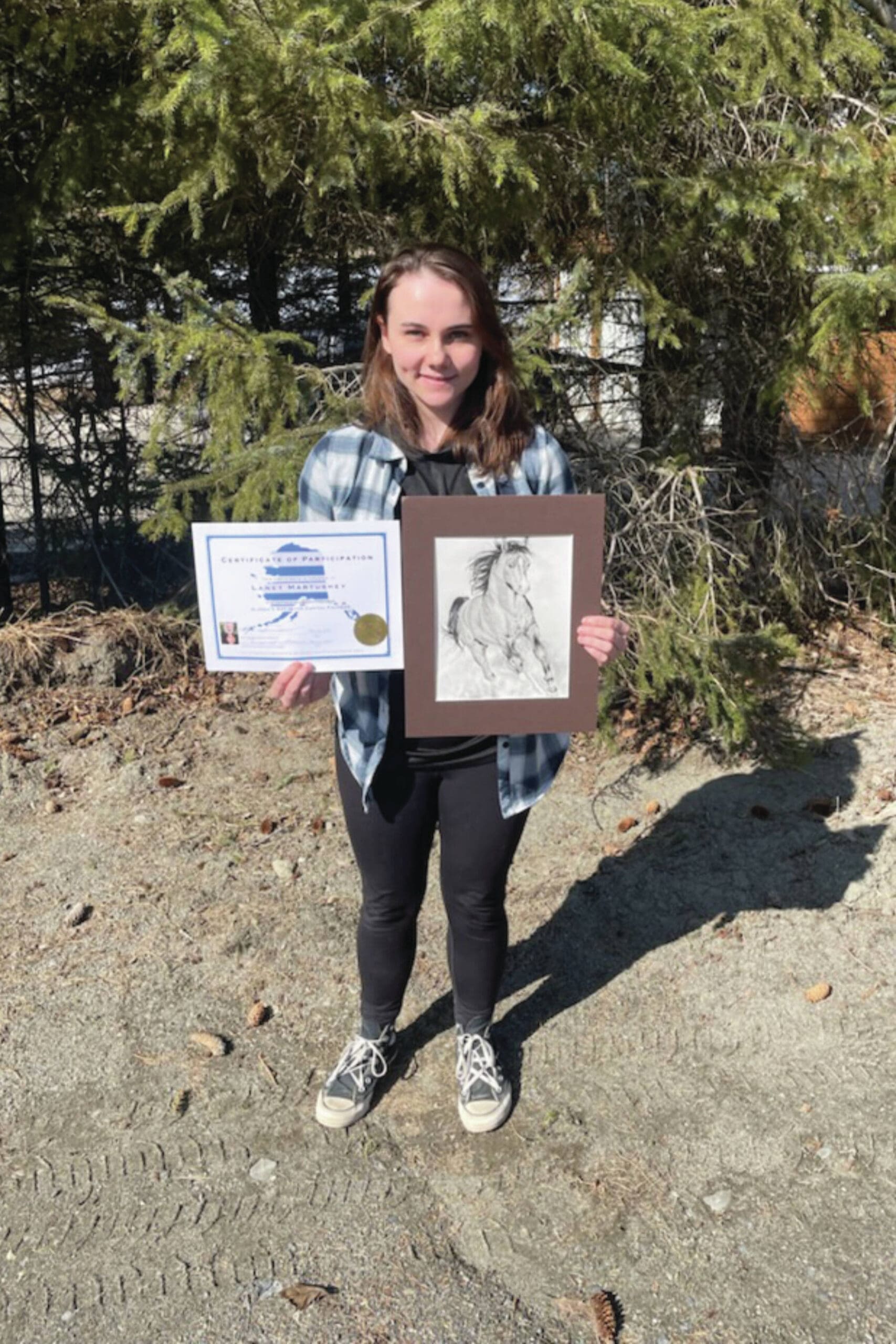 Photo by Emilie Springer/Homer News
Laney Martushev poses at the Homer News office with her certificate from Art in the Capitol and one of the pieces she had on display in Juneau.