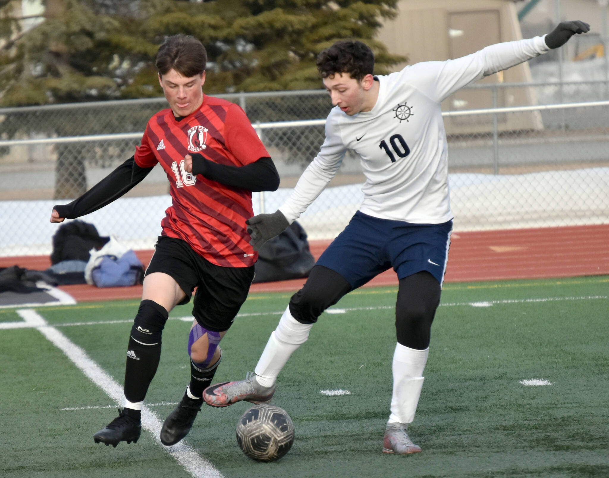 Kenai Central’s Sawyer Vann and Homer’s Lucas Story battle for the ball Tuesday, April 16, 2024, at Ed Hollier Field at Kenai Central High School in Kenai, Alaska. (Photo by Jeff Helminiak/Peninsula Clarion)