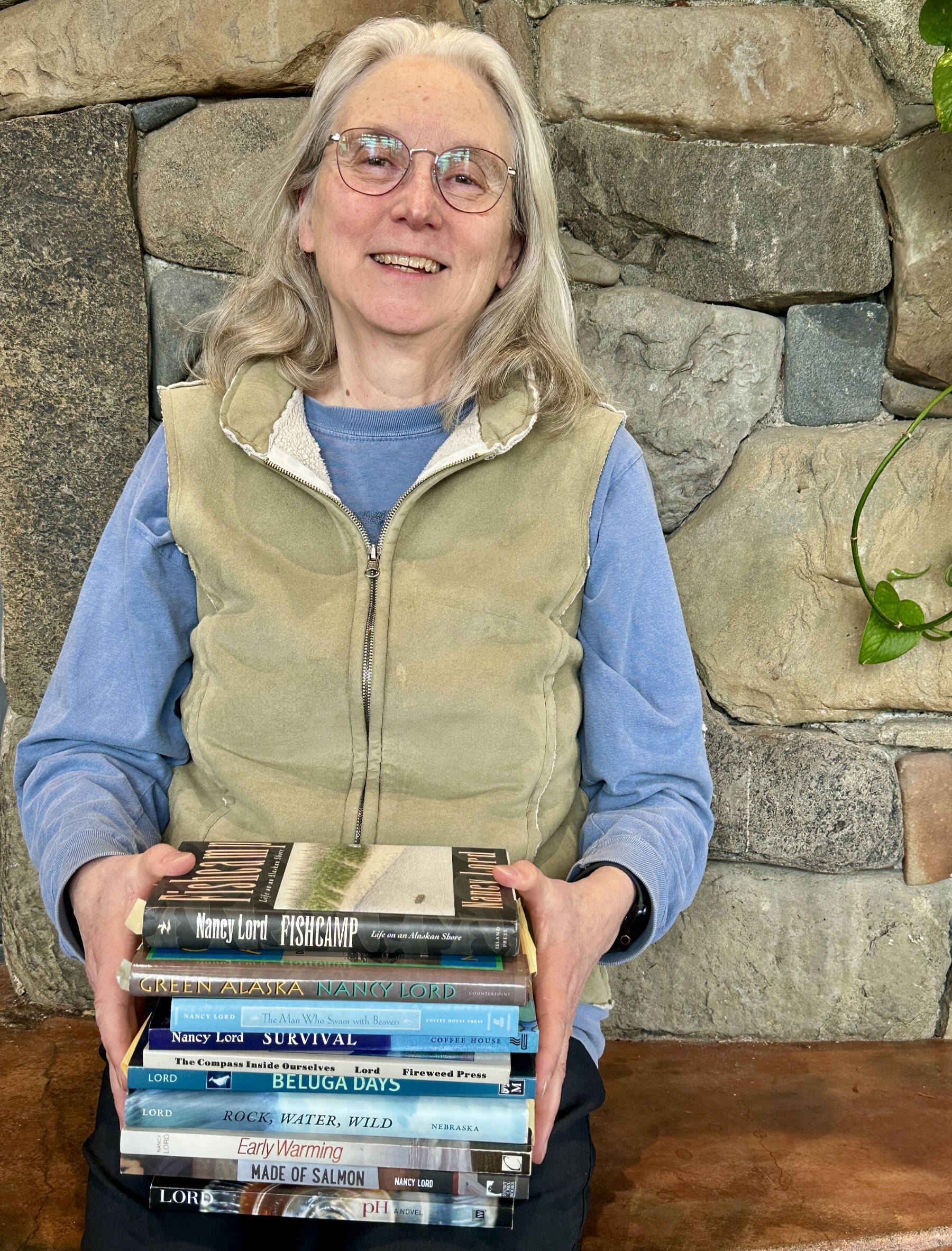 Homer author Nancy Lord poses with a stack of her published books at the Homer Public Library in April 2024. Photo by Christina Whiting