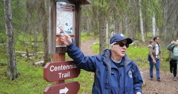 A guide from the Kenai National Wildlife Refuge leads visitors on a hike of Centennial Trail near Soldotna on Saturday, June 1, 2024. (Jake Dye/Peninsula Clarion)