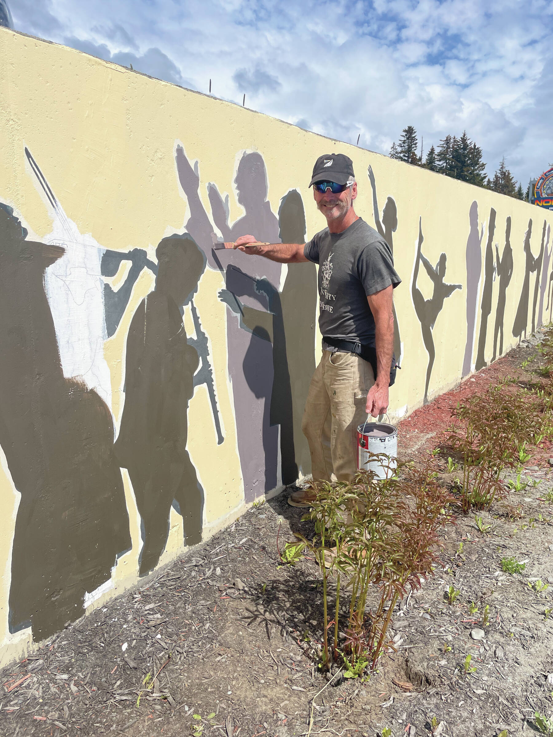 Oregon artist Tom Reed repaints the image of Mark Robinson featured in a mural of Homer performing artists, located in front of Nomar on Pioneer Avenue, on Tuesday, June 11<ins>, 2024, in Homer, Alaska</ins>. (Photo by Emilie Springer/Homer News)