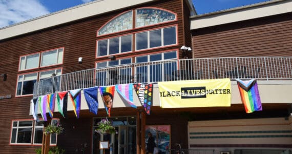 Pride flags adorn the upper balcony on Kachemak Bay Campus's Pioneer Hall during the Homer Pride Liberation Celebration held in the parking lot on Saturday, June 15, 2024, in Homer, Alaska. (Delcenia Cosman/Homer News)