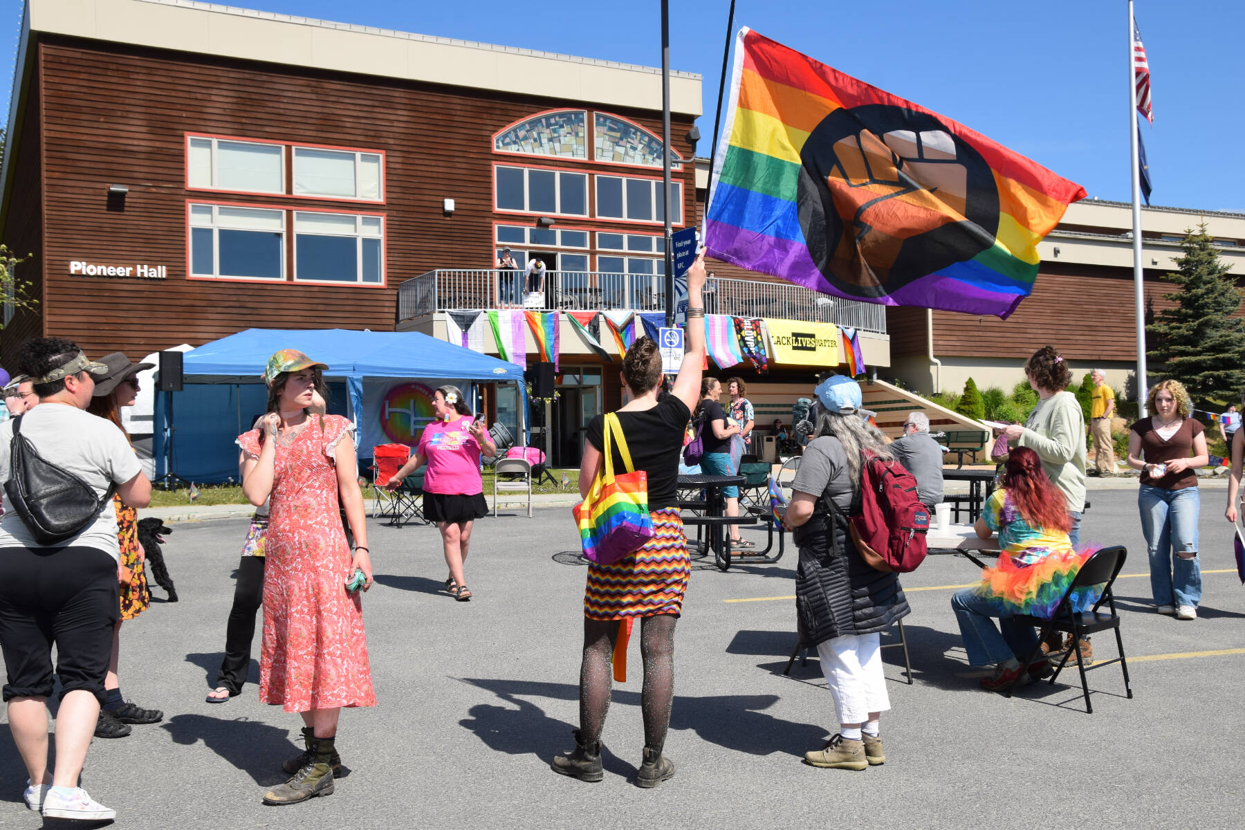 An attendee of the Homer Pride Liberation Celebration on Saturday, June 15, 2024, holds up a BLM Pride flag in the Kachemak Bay Campus parking lot in Homer, Alaska. (Delcenia Cosman/Homer News)